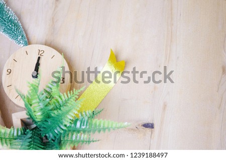 Brown gift box, gold ribbon, wooden clock, green christmas tree on On brown wood floor.