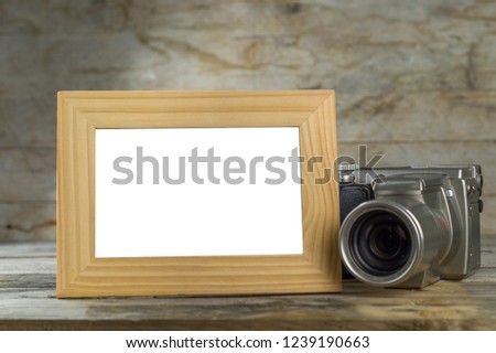 Digital camera and empty picture frame on a wooden table. Copy space for your own text or picture.