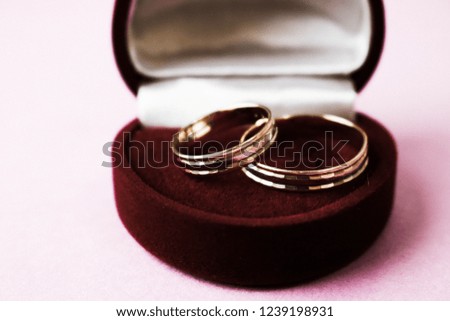 A beautiful red festive gift box velvet for two engagement, wedding rings with precious gold round precious pile rings. Concept: marriage proposal, wedding, engagement.