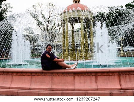 pictured in the photo a young girl sits on a large beautiful fountain