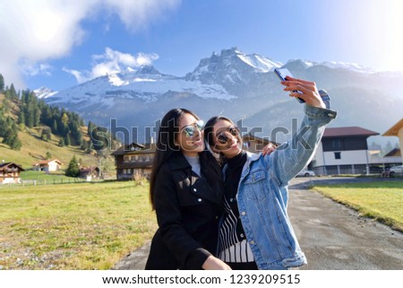 Selfie lifestyle portrait of young best friends girls having fun together at kandersteg, Switzerland. Travel concept,happy girls make picture together and having fun, make funny faces on camera.