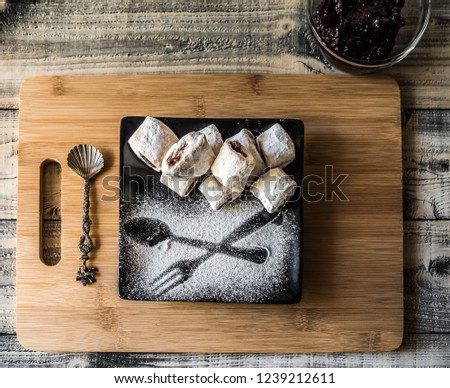 Sweet shortcrust pastry croissants in crescent shape filled with jam on black plate. Traditional romanian cornulete with jam and powdered sugar.  Royalty-Free Stock Photo #1239212611