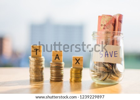 coin of money on wooden table and text TAX SAVE with blur background.