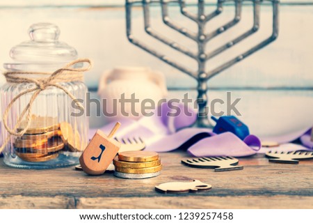 Dreidel, menorah ,hanukkah coins or hanukkah gelt in a glass jar,jug. Dark marble background. Translation: G

