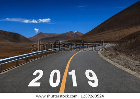 2019 painted on asphalt road with mountains 