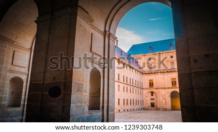 View of courtyard of the Kings through an arch at Basilica at the monastery and royal residence of Spanish kings, San Lorenzo de El Escorial near the Spanish capital city of Madrid at sunset