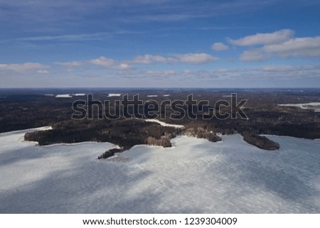 Aerial view of frozen lake stretching to the horizon in winter against a blue sky. Photo of the northern nature of Finland with a drone.