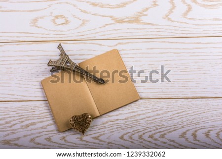 Eiffel tower miniature and a steel heart on a brown notebook on a wooden background