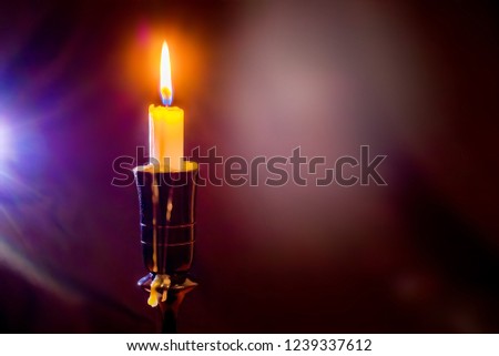 A candle lit brightly on the candlestick. Candle on a dark abstract background. Free space