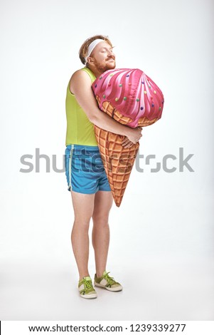 Funny picture of red haired, bearded, plump man on white background. Man holding a big ice cream
