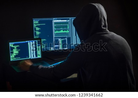 hacker in front of two monitors with computer code Royalty-Free Stock Photo #1239341662