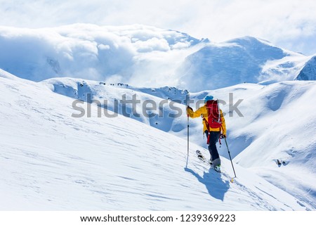 A skier is walking up the hill. Skitouring in Alps. Sunny weather. Royalty-Free Stock Photo #1239369223