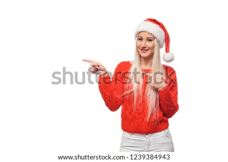 Christmas  woman in Santa hat is showing to the left blank empty billboard. Space for text, sale