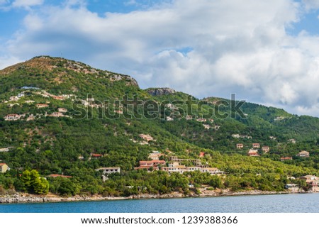 Picturesque coastal landscape of Corfu Island, Greece. Dark cloudy sky and green hills along the coast.