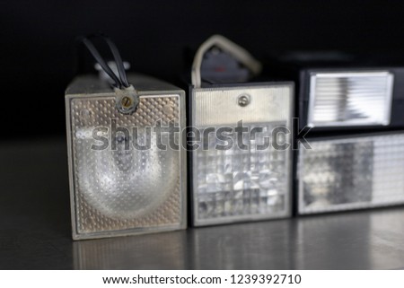 Old flash lamps on a metal table. Photo accessories from central europe. Dark background.