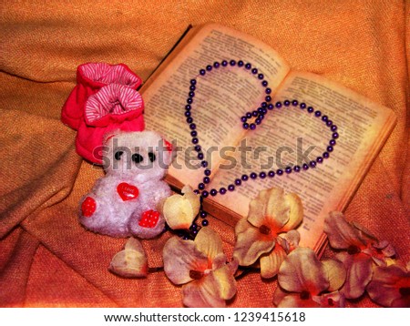 Old book. Open book. Reading. Book page. Sprig of flowers on the book.History. Education.Teddy bear. Beaded heart. Children's tops. Background. 