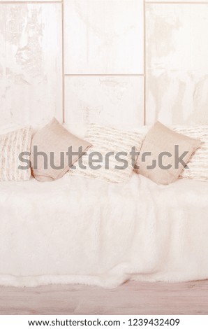 Many pillows lie on the couch, which is covered with a large plush veil against the background of a marble wall