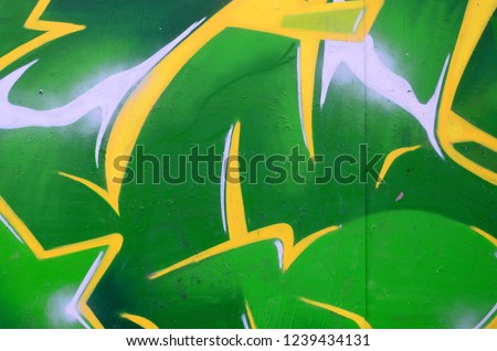 Fragment of graffiti drawings. The old wall decorated with paint stains in the style of street art culture. Colored background texture