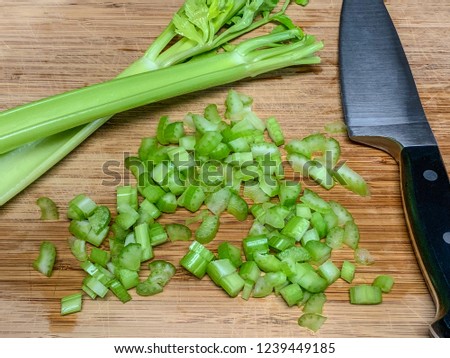 Fresh green celery stems and knife on wooden cutting board 