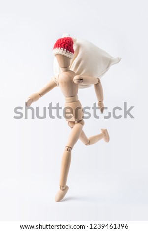 Business and design concept - running wooden mannequin with red hat and gift bag like santa claus isolated on white background