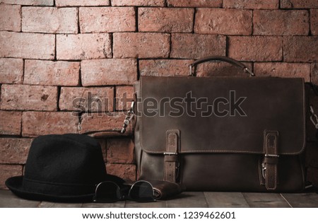 vintage leather bag with sunglasses and hat on wood table, accessories hipster style, prepare for Travel concept and vintage tone