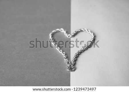 Texture of a beautiful golden festive chain unique weaving in the shape of a heart on a black and white background and copy place. Concept: love, marriage proposal, marriage, St. Valentine's Day.