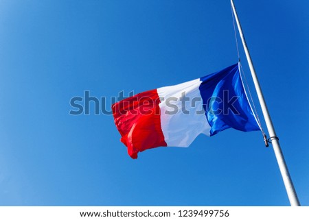 Lowered to half-staff flag of France over blue sky