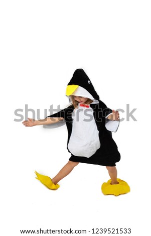 A little girl in penguin clothes is dancing on a wrinkle on a white background