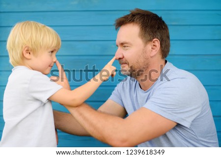 Cute little boy and his father pressed finger on each other's nose. Games with young childs.