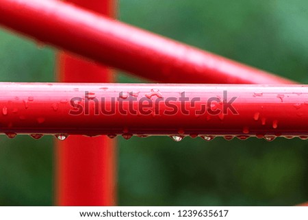 Water droplets on a metallic red construction is close