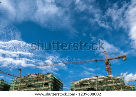 Tower crane at the construction site of blue sky and white clouds.