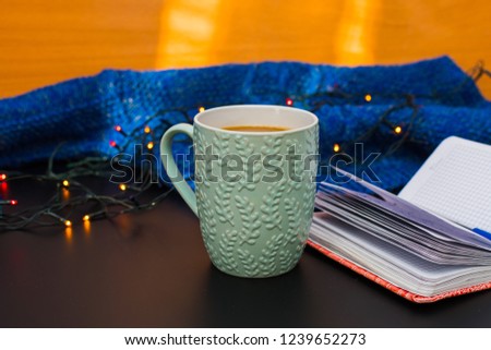 notebook and mug surrounded by garlands and sweaters