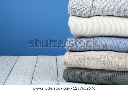 Knitted wool sweaters. Pile of knitted winter, autumn clothes on blue, wooden background, sweaters, knitwear, space for text