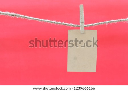 Blank brown note on clothesline and red background for design in your Christmas concept.
