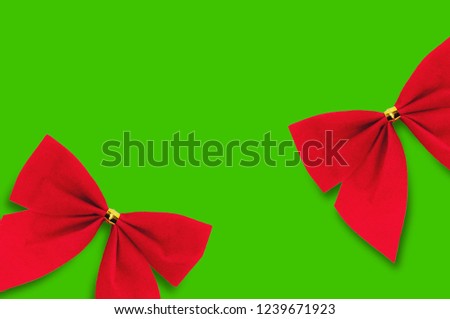 Two red textile bows on green background with copy space for your text
