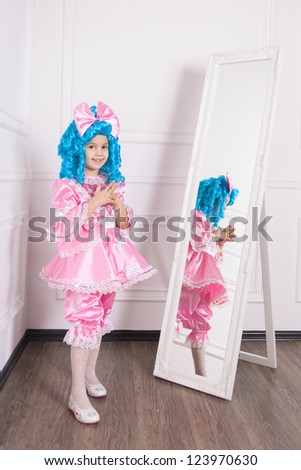 Cute girl dressed like Malvina posing next to the mirror in studio