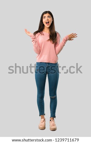 Full body of Teenager girl with pink shirt with surprise and shocked facial expression on isolated grey background