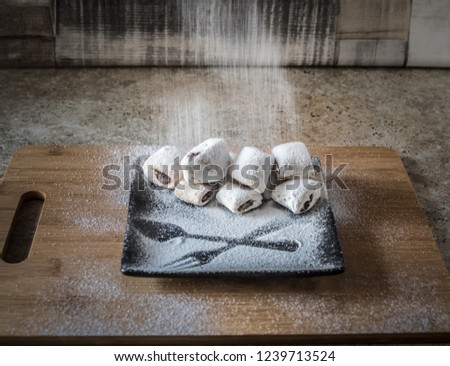 Pouring sugar powder on sweet shortcrust pastry croissants.  Traditional romanian cornulete with jam and powdered sugar.  Royalty-Free Stock Photo #1239713524