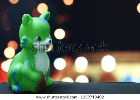 Cute Green rubber Toy Cat with ball in hand in different bokeh background with copy space