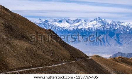 A long road leading to a large snow capped mountain on a sunny day in Leh Ladakh