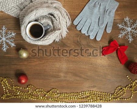 Cup of coffee in wool cozy scarf and mittens on wood table background. Holiday winter decoration and concept. Copy space.