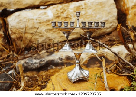 Hanukkah Menorah. Jewish candlestick in style Jewish star Magen David. Image of Jewish holiday Hanukkah, Israel. Background: sawed wood (stump) and natural stones