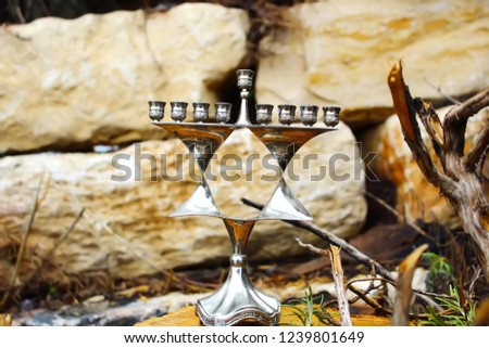 Hanukkah Menorah. Jewish candlestick in style Jewish star Magen David. Image of Jewish holiday Hanukkah. Background: sawed wood (stump) and natural stones. Israel