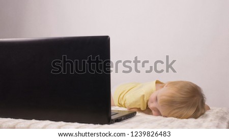 little girl is lying and looking at the computer screen, laptop, white background, watching cartoons