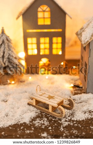 Toy for the Christmas tree on the background of Christmas decorations. Wooden sled. Free space for text. Selective focus. Background for a Christmas card