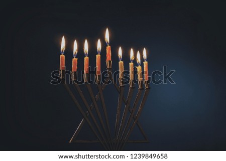 Menorah with colorful candles for Hanukkah on light blue background, close up
