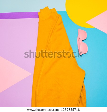 Woman's yellow pullover with pink sunglasses on memphis style background. Minimal concept. Fall and winter fashion. 