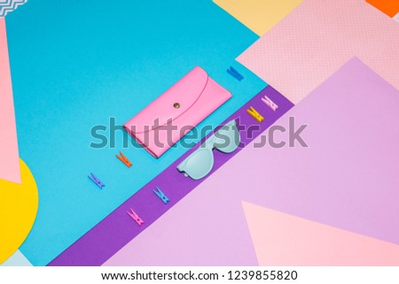 Woman's fashion set with pink purse and blue painted sunglasses on memphis style background. Geometry concept 