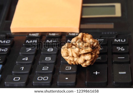 Concept Calculator with close-up numbers - walnut on the table calculator keyboard and yellow paper with text copy space, brain symbol
