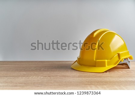 Yellow engineer hat place on wooden table with white background and copy space. Industrial successful concept photography.